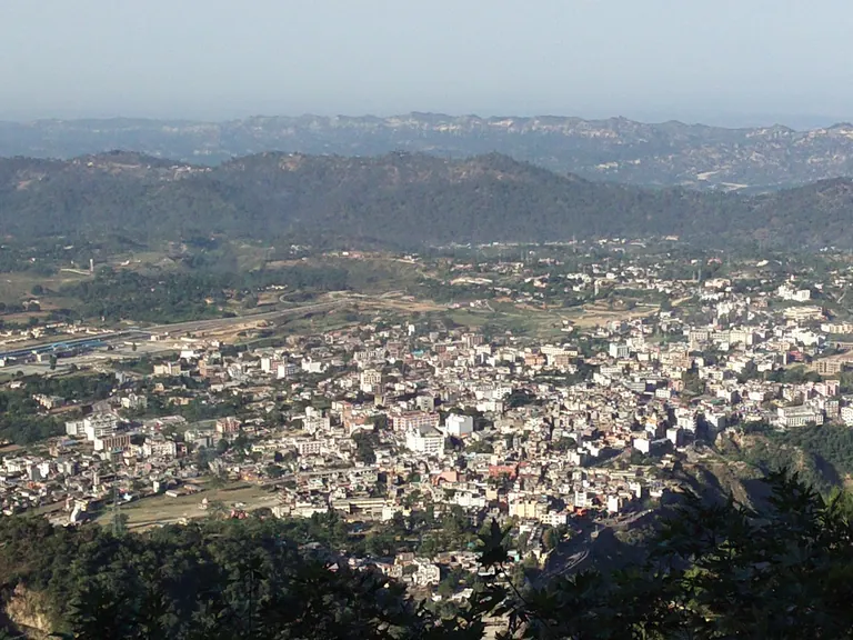 Dense buildings of Katra town seen from high on the hillside, with hills on the horizon