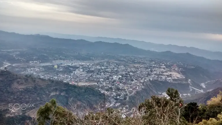 Wide view over Katra town spread across the valley floor, surrounded by layered hills