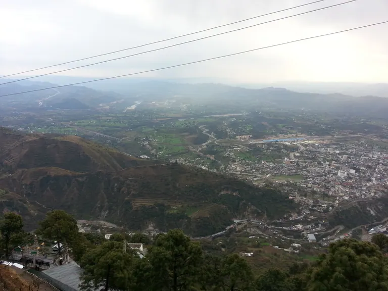 Hazy view of the Katra valley with the town in the distance and green slopes in the foreground