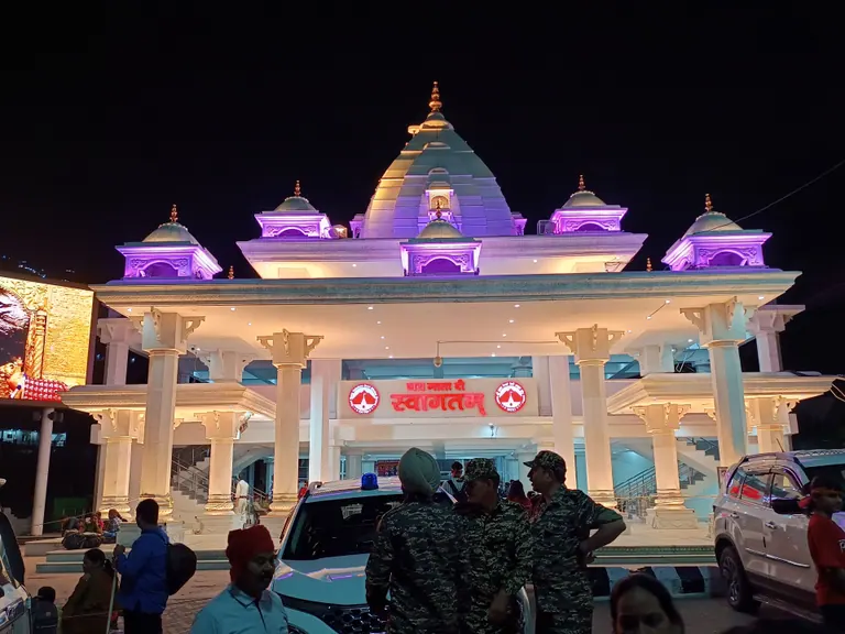 An ornate illuminated entrance gate with domed pavilions at the start of the Vaishno Devi yatra in Katra at night